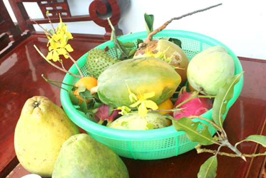 Rổ trái cây đặt trên bàn gồm nhiều loại quả bưởi, dừa, thanh long, mãng cầu.