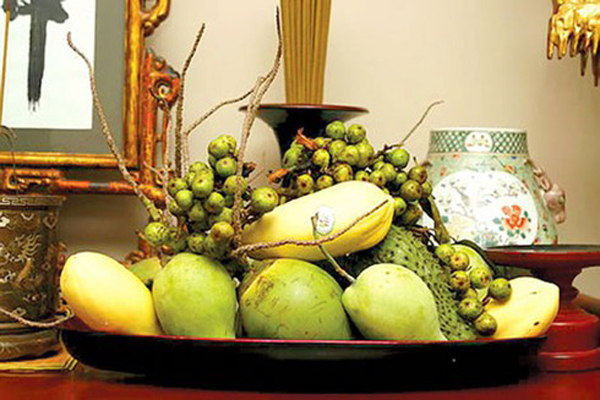 Đĩa trái cây lớn trên bàn thờ gồm nhiều loại quả màu xanh.