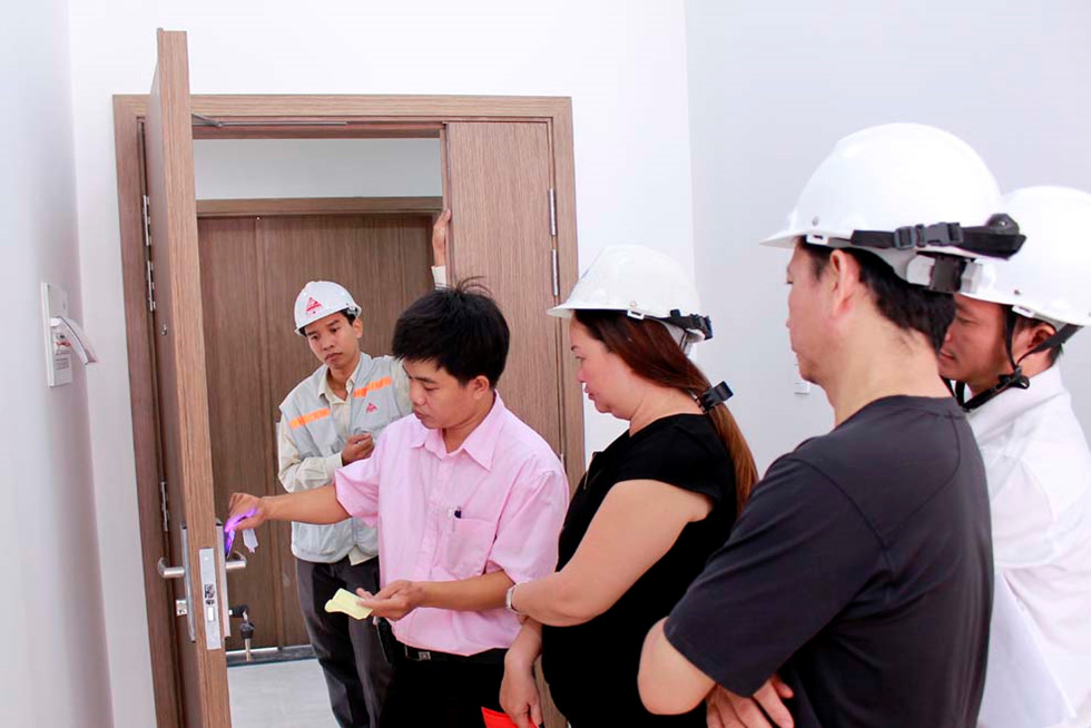 Người mua có thể từ chối nhận bàn giao nhà sai thiết kế. 5 người đứng cạnh cửa ra vào của một ngôi nhà